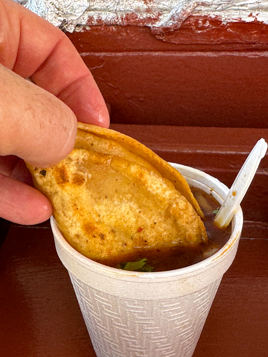 Dipping a Birria Taco in Consomme